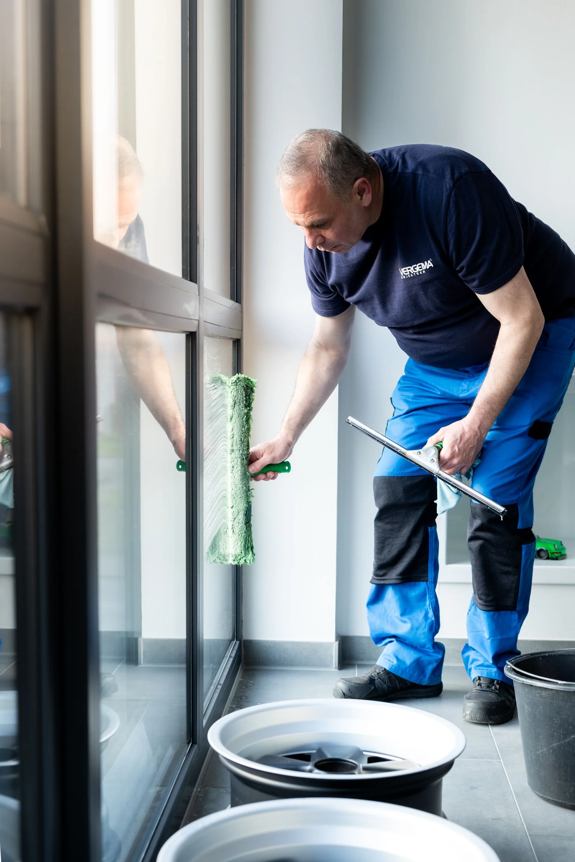 Gewerbliche Reinigung in Herne: Fachkraft für Unterhaltsreinigung säubert gründlich die Fensterfront einer Gewerbefläche.